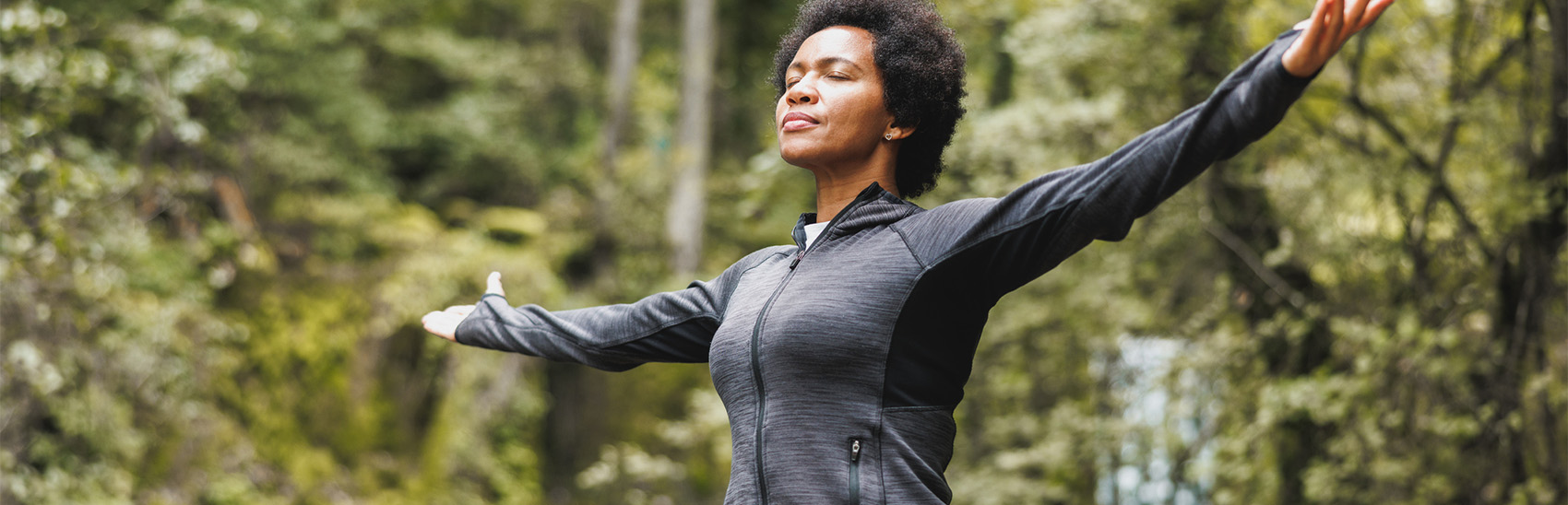 A lady experiencing peace out in the woods after her pain has been relieved.