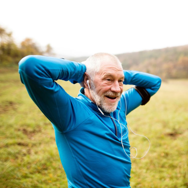 A man listening to music while exercising, stretching his arms that are now relieved from pain.