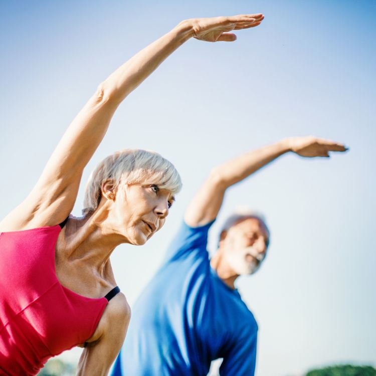 A couple doing yoga stretches outside.