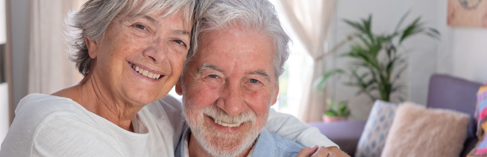 An elderly couple hugging and smiling now they they feel relieved of pain.